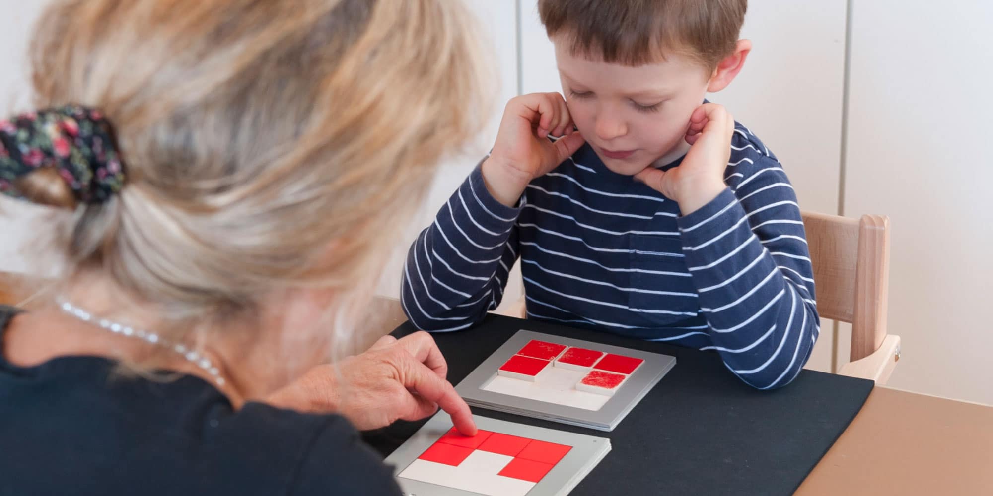 Ein Foto einer Heilpädagogin, die in der Diagnostik mit einem Jungen ein Spiel spielt. Erstberatung.